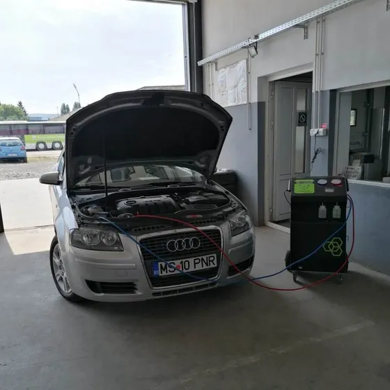 Autoturism conectat la stația de service pentru aer condiționat, în atelierul de vulcanizare